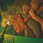 A candle lighting up images of a monkey and rhino on an escape room wall